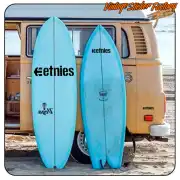 Black etnies logo applied to two surfboards beside a camper van