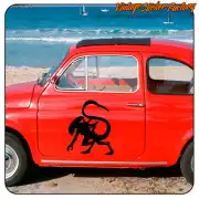 Pegatina Predator aplicada en la puerta de un coche clásico rojo junto a la playa