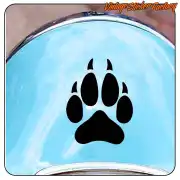 Pegatina negra con huella de perro aplicada sobre una superficie azul curva.