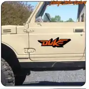 Logo Duke bicolor naranja y negro colocado en la puerta lateral de un vehículo