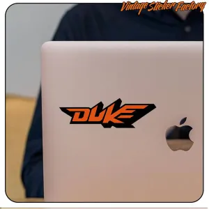 Two-tone orange and black Duke logo sticker applied to a laptop lid
