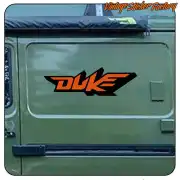 Zweifarbiges orange-schwarzes Duke-Logo an der Seite eines grünen Fahrzeugs
