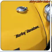 Texte Harley-Davidson noir appliqué sur une surface jaune à côté d’un bouchon métallique