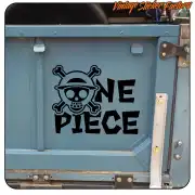 Pegatina de calavera con sombrero y texto ONE PIECE aplicada en la puerta de un baúl azul