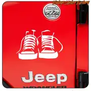 Dos zapatillas blancas sobre una puerta roja de Jeep Wrangler