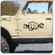 Diseño de puño sujetando dos llaves inglesas aplicado en la puerta de un vehículo todoterreno