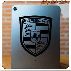 Schwarzes Porsche-Emblem auf der Rückseite eines Tablets angebracht