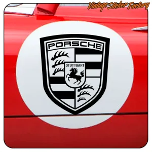 Emblema Porsche en blanco y negro aplicado sobre la carrocería roja de un vehículo