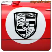 Emblème Porsche noir et blanc appliqué sur la carrosserie rouge d’un véhicule