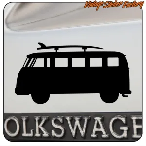 Silhouette noire d’un van camper avec planche de surf sur une surface portant le texte Volkswagen