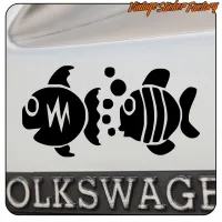 Close-up of two black adhesive fish on a vehicle number plate area