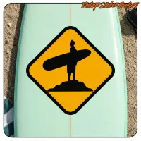 Silhouette de surfeur avec planche sur fond jaune, appliquée sur une planche de surf
