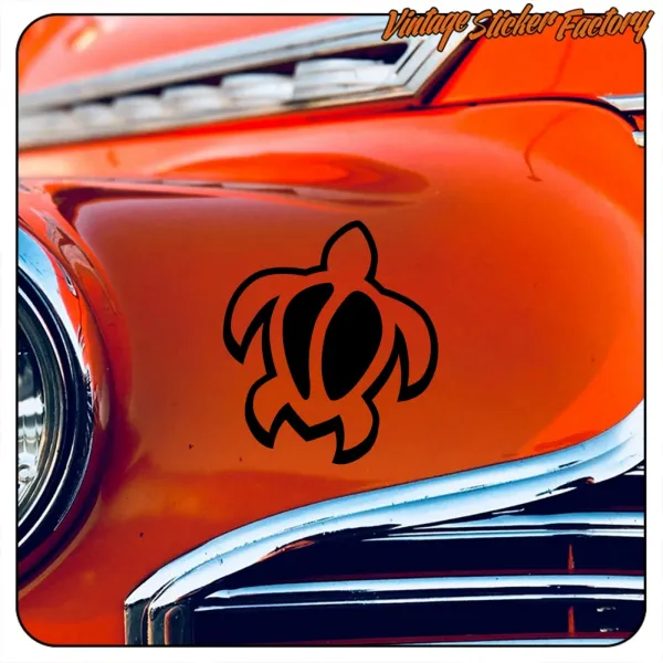 Close-up of a black tribal turtle placed on the bodywork of an orange vehicle