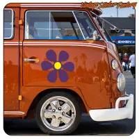 Detail einer lila und gelben Blume an der Seite eines klassischen orangefarbenen Transporters
