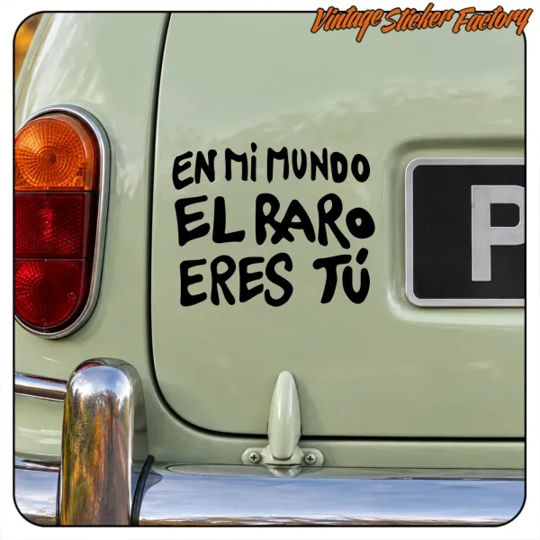 Pegatina negra «En mi mundo el raro eres tú» aplicada en la parte trasera de un coche clásico verde