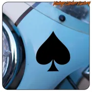 Pegatina negra de as de picas aplicada junto al faro de un vehículo azul.