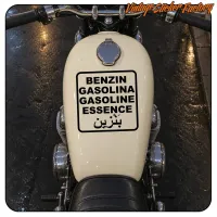 Vinilo rectangular con texto sobre el depósito visto desde el asiento de una moto