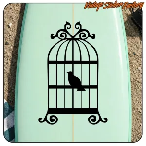 Cage décorative noire avec un oiseau appliquée sur une planche vert clair
