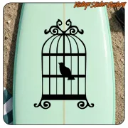 Cage décorative noire avec un oiseau appliquée sur une planche vert clair