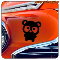 Ourson noir appliqué sur la carrosserie orange d’une voiture ancienne