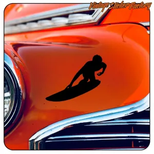 Silhouette d’un surfeur sur une planche appliquée sur la carrosserie orange d’une voiture classique