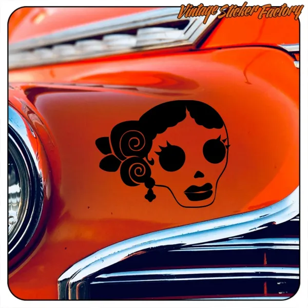 Detalle de calavera estilizada en negro sobre la carrocería naranja de un automóvil clásico