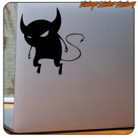 Detalle de pegatina de demonio negro con cola sobre un portátil