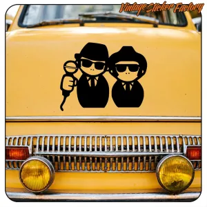 Pegatina de dos figuras con sombrero aplicada en la parte frontal de un coche amarillo