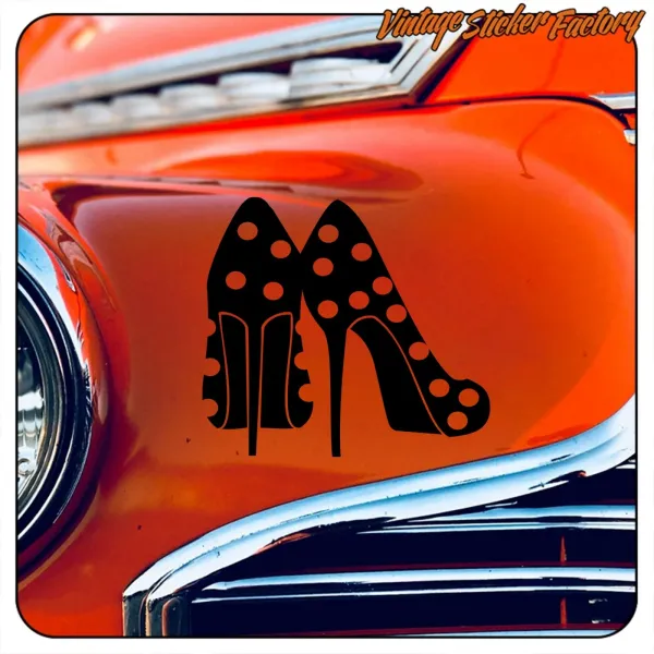 Schwarzes Design mit gepunkteten Schuhen mit hohen Absätzen auf der orangefarbenen Karosserie eines klassischen Autos