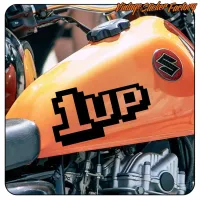 Ansicht des 1UP-Aufklebers auf dem orangefarbenen Tank eines Motorrads