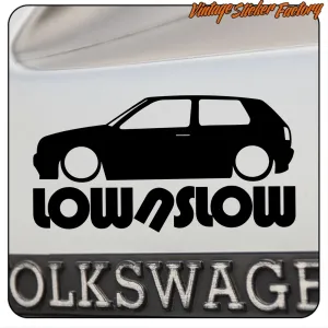 Détail de l’autocollant « LOW/SLOW » avec silhouette de Volkswagen Golf sur une surface blanche.