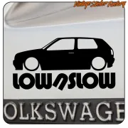 Close-up of the «LOW/SLOW» sticker with a Volkswagen Golf silhouette on a white surface.