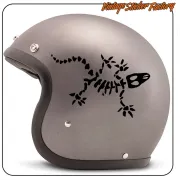 Casco gris con el diseño negro de gecko formado por huesos y una calavera