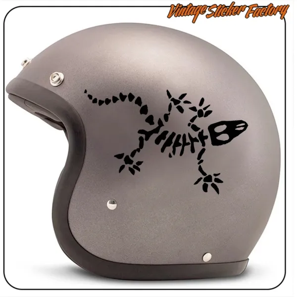 Side view of a grey helmet decorated with a bony gecko and a black skull