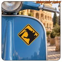 Detalle de la pegatina CAUTION GODZILLA sobre el frontal azul de una scooter