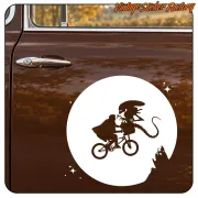 Vinilo blanco de alienígena en bicicleta ante la luna aplicado en una puerta marrón