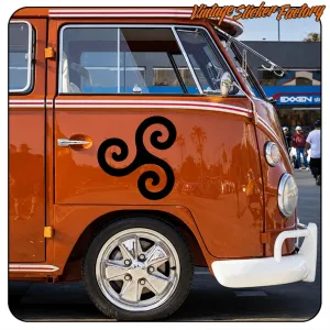 Triskèle noir appliqué sur le côté d’un camping-car orange