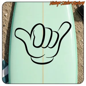 Sticker Shaka noir appliqué sur une planche de surf vert clair