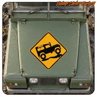 Design de véhicule tout-terrain noir sur panneau jaune présenté à l’avant d’un véhicule vert
