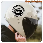 Pegatina negra con todoterreno y texto circular aplicada sobre un casco blanco.