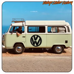 Pegatina negra con emblema VW aplicada en el lateral de una furgoneta camper clara