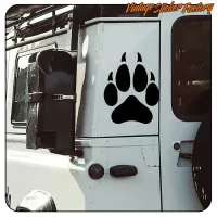 Pegatina negra de huella de perro en la carrocería lateral de una furgoneta.