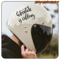 Adhesivo «Adventure is calling» colocado en un casco de moto con visera oscura