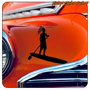 Silhouette einer Person mit Dreadlocks auf einem SUP-Board, auf der orangefarbenen Karosserie eines Oldtimers angebracht