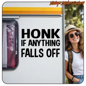 Schwarzer Text „HONK IF ANYTHING FALLS OFF“ auf der weißen Seite eines Wohnmobils