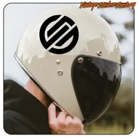 Black circular sticker placed on a light-coloured motorcycle helmet