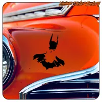 Detail des schwarzen Batman-Aufklebers auf der orangefarbenen Karosserie eines klassischen Autos