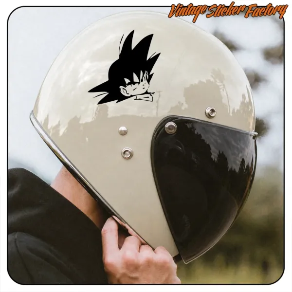 Detalle de un casco de moto con el adhesivo de Goku en la parte superior