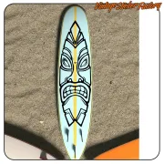 Diseño tiki negro sobre una tabla de surf clara con franja amarilla central