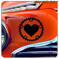 Detail des schwarzen Herzdesigns in einem Fahrradkettenblatt auf klassischer orangefarbener Karosserie